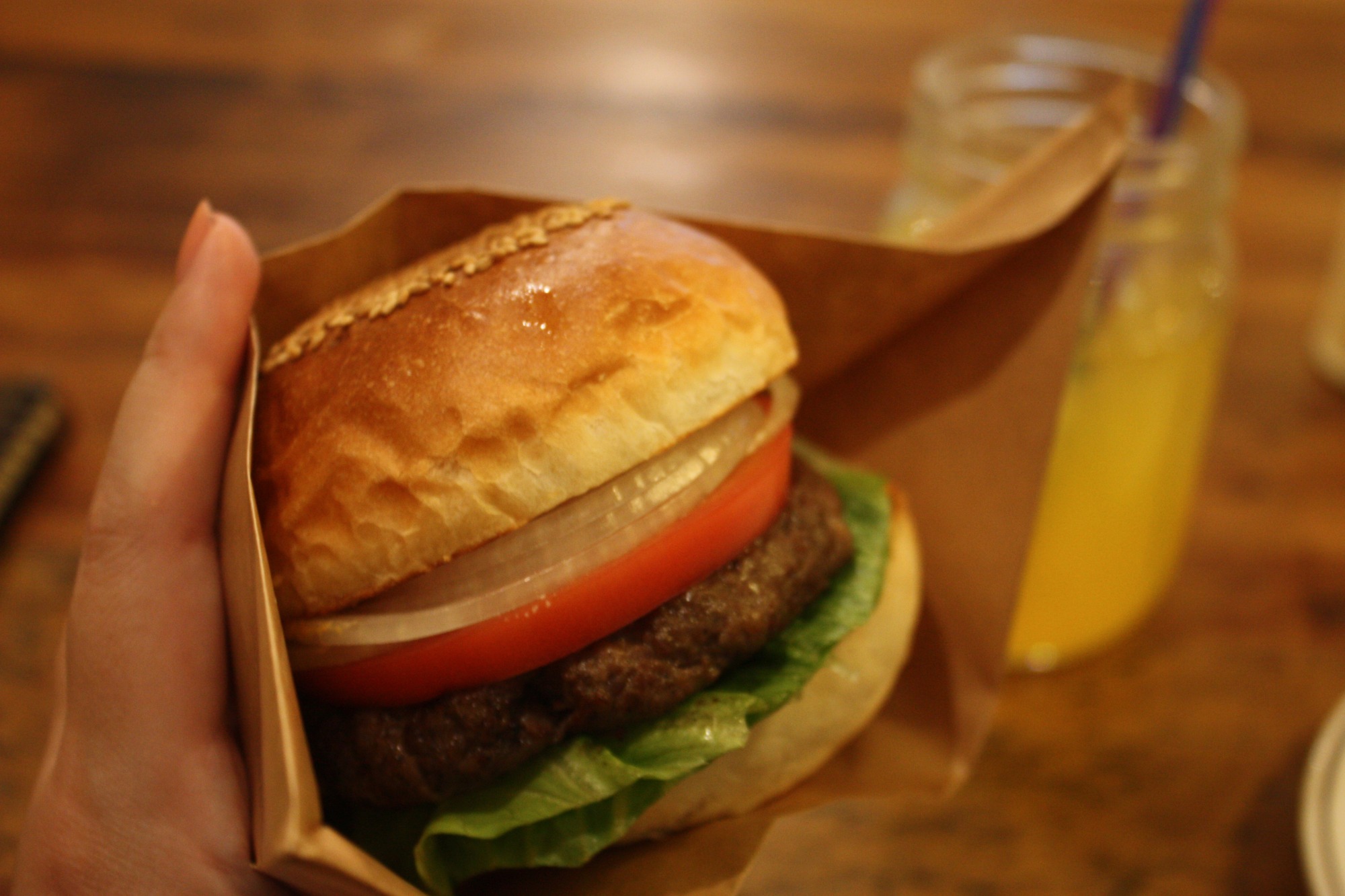 飛騨牛100%のハンバーガーを片手で持ち上げた様子